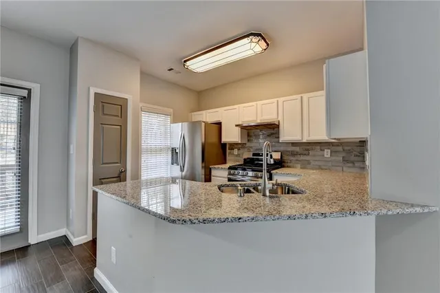 a kitchen with stainless steel appliances granite countertop a sink refrigerator and cabinets