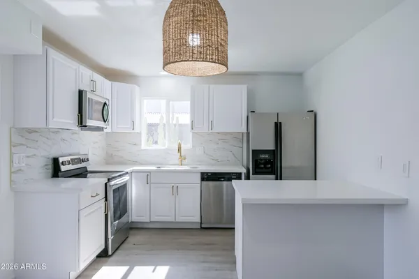 a kitchen with stainless steel appliances kitchen island a refrigerator sink and cabinets