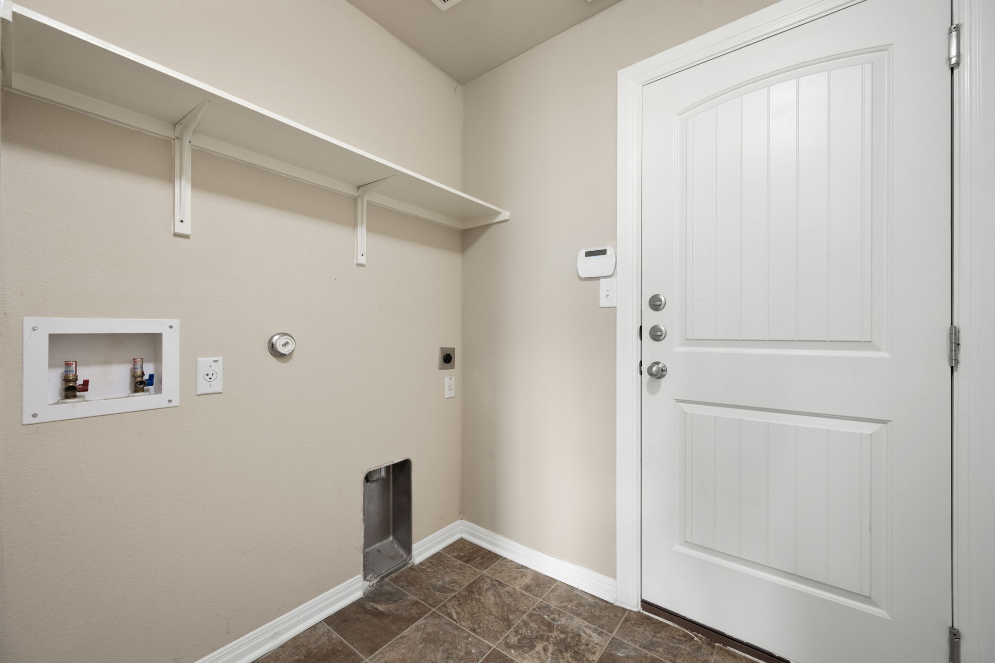 12701 Carillon Way Manor, TX 78653 - Photo 11 of 20 Utility area featuring built-in shelving, a wall-mounted door, and tile flooring