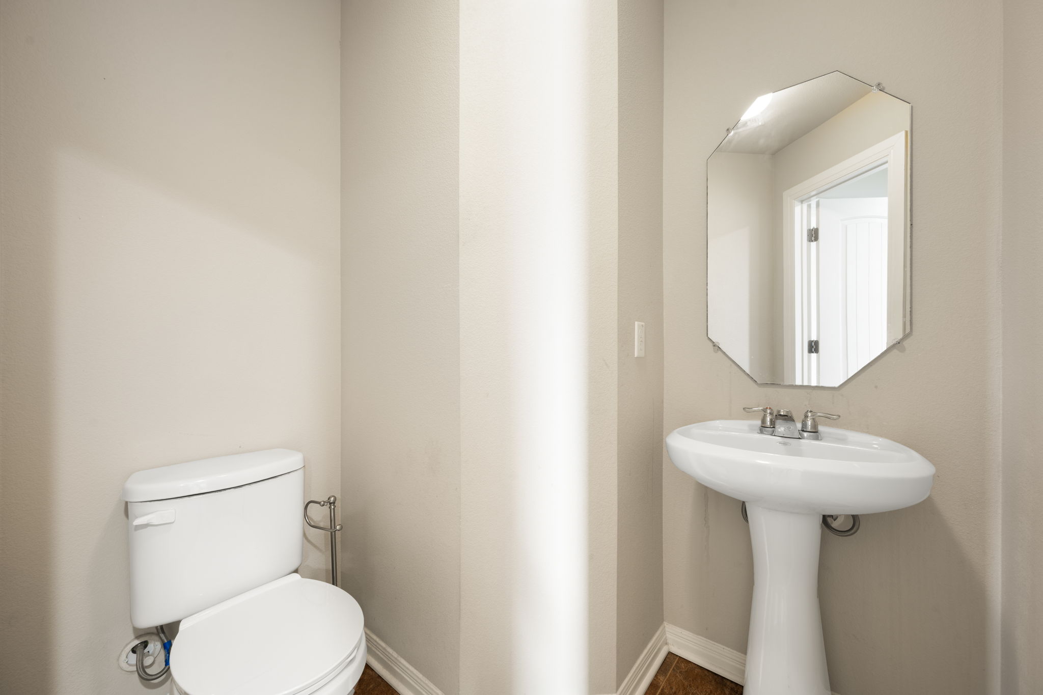 12701 Carillon Way Manor, TX 78653 - Photo 12 of 20 White pedestal sink with a polished chrome faucet, complementing an octagonal wall-mounted mirror