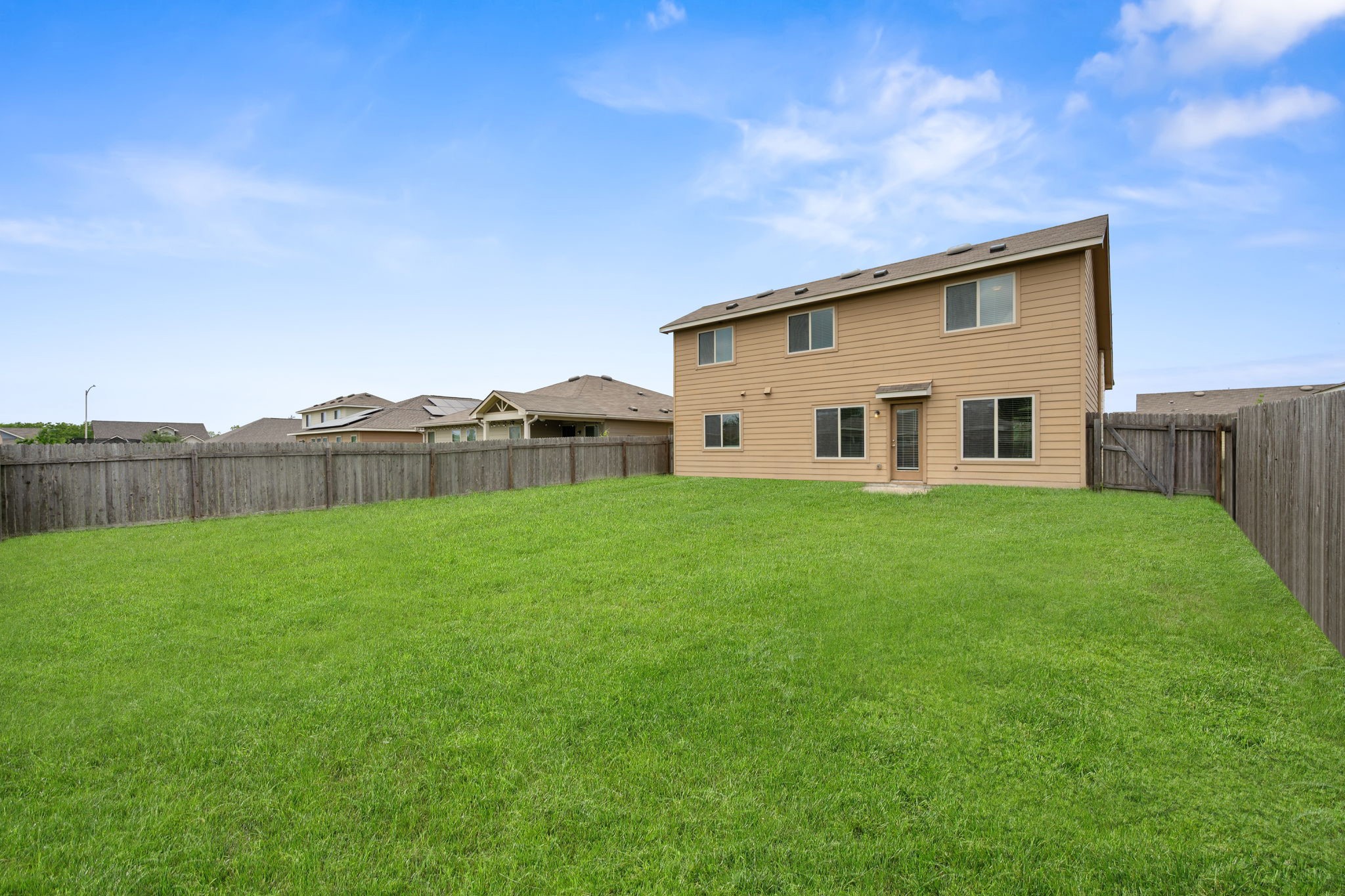 12701 Carillon Way Manor, TX 78653 - Photo 19 of 20 Expansive backyard featuring a lush lawn, privacy fencing, and direct access to the dwelling