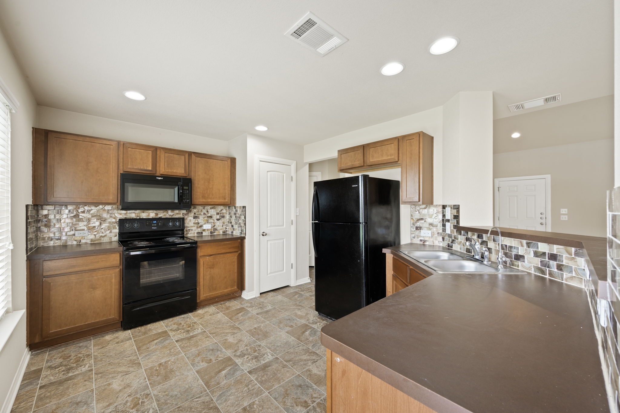 12701 Carillon Way Manor, TX 78653 - Photo 5 of 20 Kitchen featuring wood cabinetry, dark countertops, and a mosaic tile backsplash