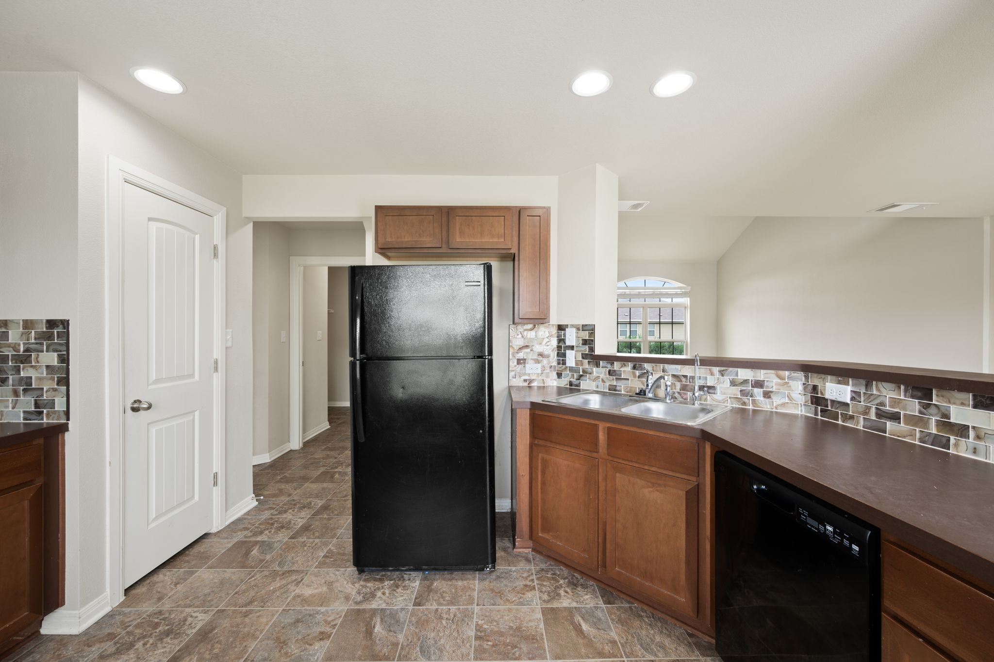12701 Carillon Way Manor, TX 78653 - Photo 6 of 20 Kitchen featuring wood-finish cabinetry, black appliances, mosaic tile backsplash, and recessed lighting