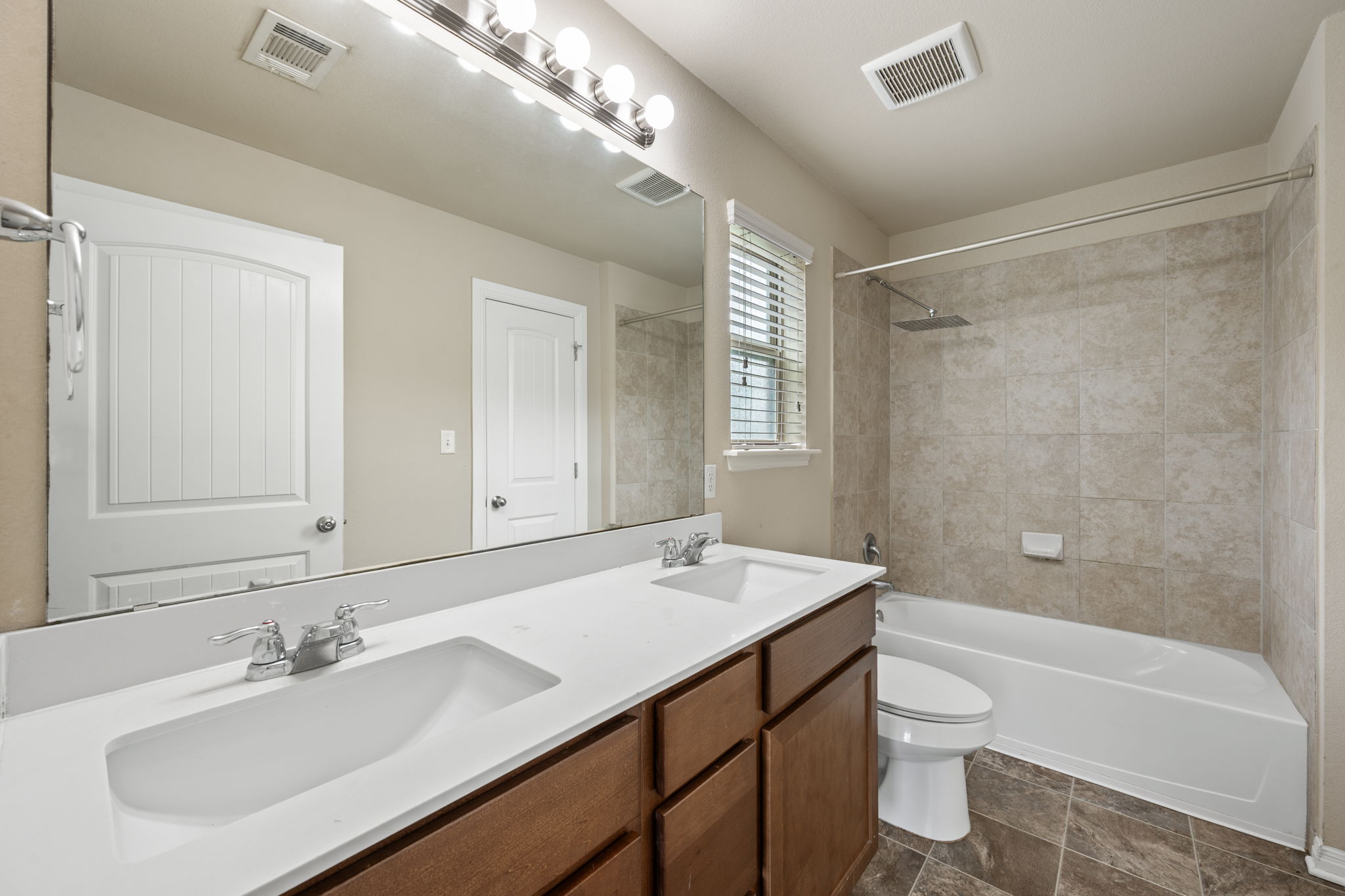 12701 Carillon Way Manor, TX 78653 - Photo 9 of 20 Bathroom featuring a dual-sink vanity with white countertops, wood-finish cabinetry, and chrome fixtures