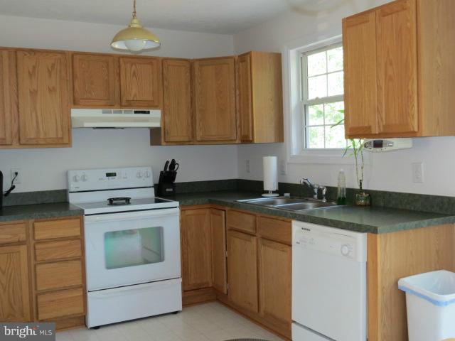 12622 Hilltop Road Lusby, MD 20657 - Photo 8 of 23 a kitchen with granite countertop white cabinets and white appliances