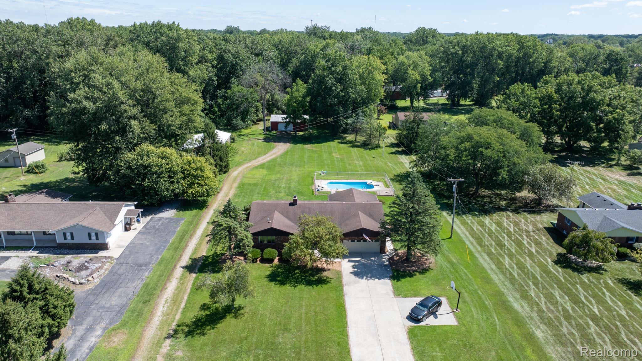 12900 Maxwell Road Carleton, MI 48117 - Photo 10 of 59 Expansive lot with lush green lawn, mature trees, and a private inground pool