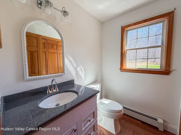 a bathroom with a granite countertop sink vanity mirror and toilet