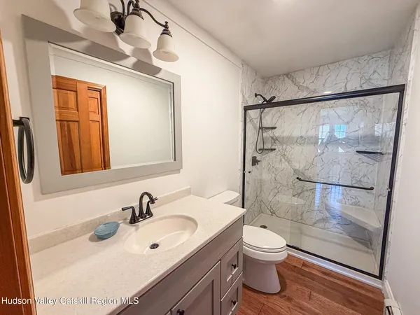 a bathroom with a granite countertop sink toilet a mirror and shower