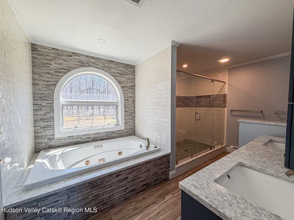 a bathroom with a granite countertop tub a sink and a large mirror