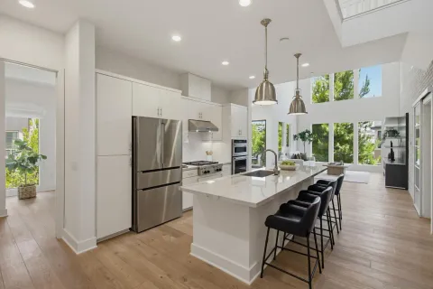 a kitchen with stainless steel appliances a dining table chairs stove and refrigerator