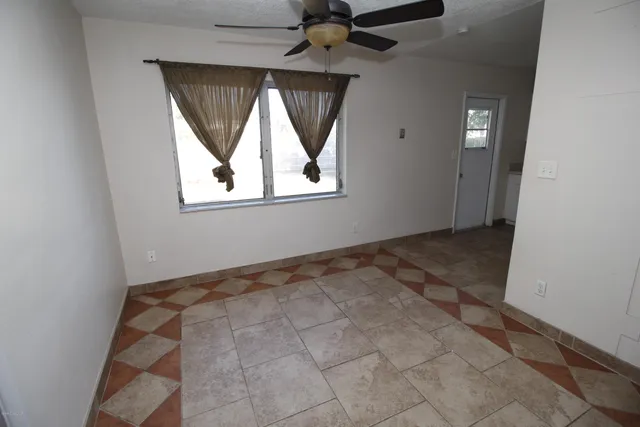 an empty room with windows and fan