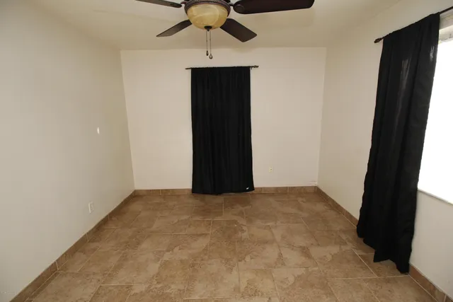 an empty room with a ceiling fan and carpet
