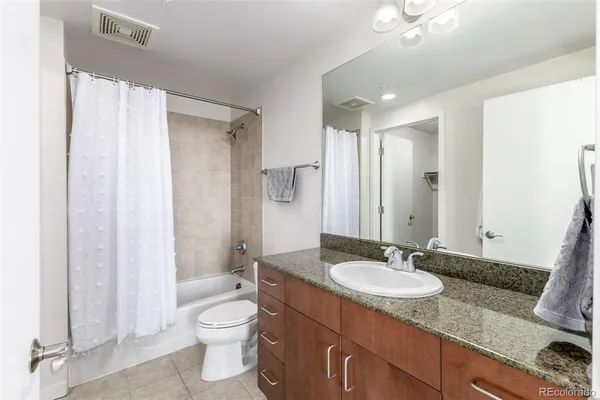 a bathroom with a granite countertop sink toilet a mirror and shower