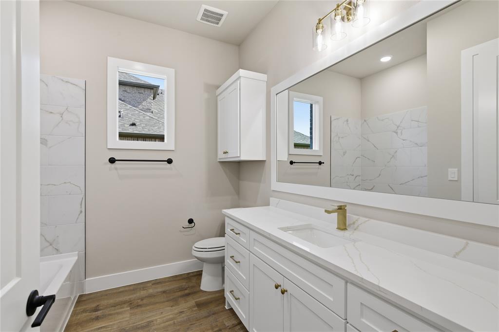 709 Anne Road Van Alstyne, TX 75495 - Photo 16 of 28 Bathroom featuring a spacious white vanity with a single sink, gold-finish faucet, and a large mirror