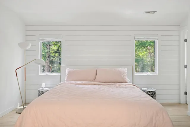 a bedroom with a bed and a window with chair