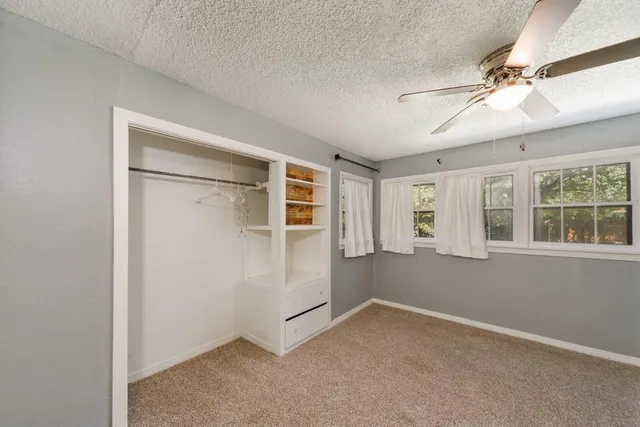 an empty room with windows and fan