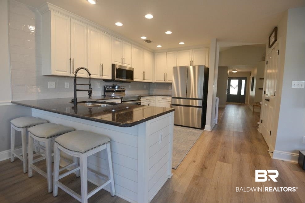 11201 Herschel Loop Daphne, AL 36526 - Photo 9 of 32 Kitchen featuring white cabinetry, light hardwood / wood-style floors, appliances with stainless steel finishes, and kitchen peninsula