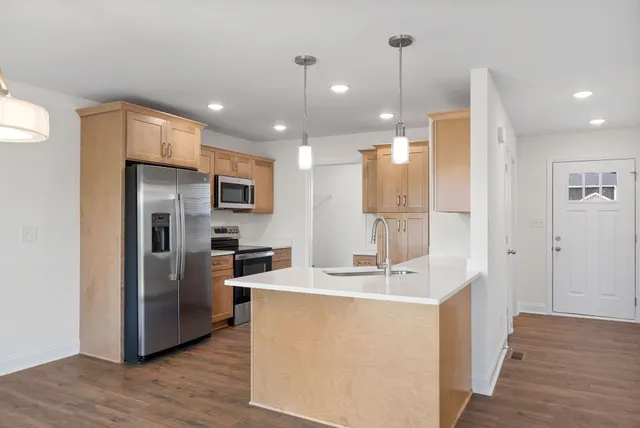 a room with stainless steel appliances kitchen island a refrigerator and a sink