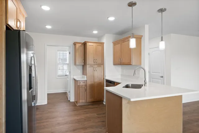 a kitchen with stainless steel appliances granite countertop a refrigerator a sink a stove and a wooden floors