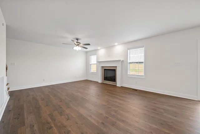 an empty room with wooden floor fireplace and windows