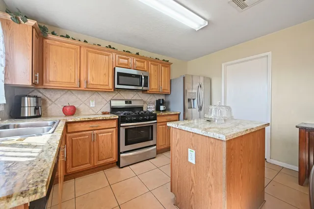 a kitchen with stainless steel appliances granite countertop a stove top oven a sink dishwasher and a refrigerator