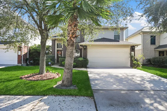 a front view of a house with a garden and trees