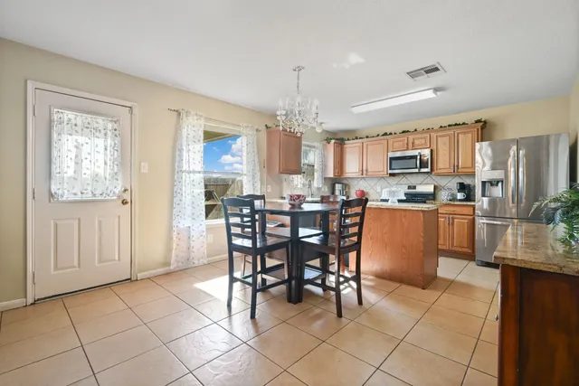 a kitchen with kitchen island granite countertop wooden cabinets a dining table and chairs