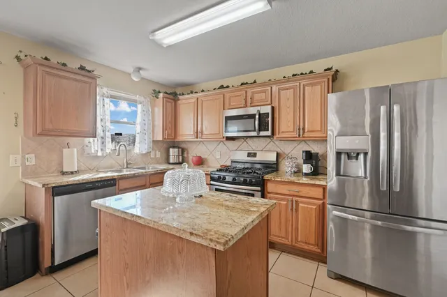 a kitchen with kitchen island granite countertop a refrigerator stove microwave and sink