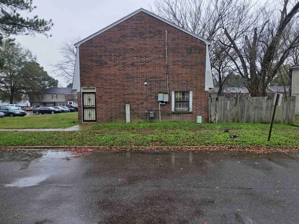 a brick building with a yard and large trees