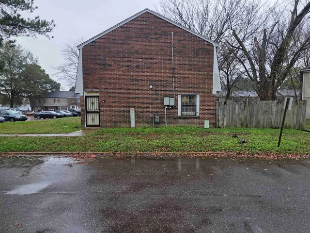 a brick building with a yard and large trees