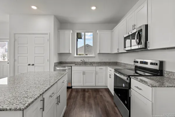 a kitchen with stainless steel appliances granite countertop wooden cabinets granite counter tops and a hard wood floors