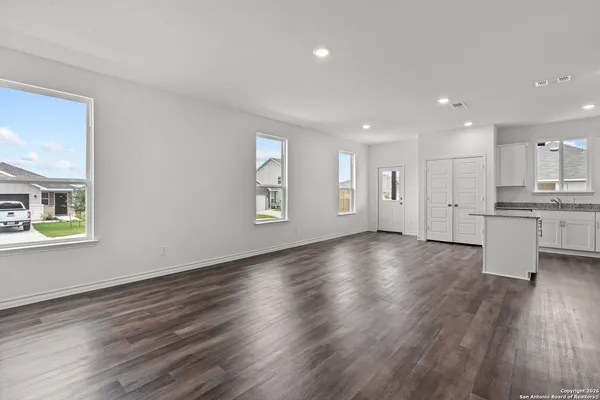 a view of an empty room with window and wooden floor