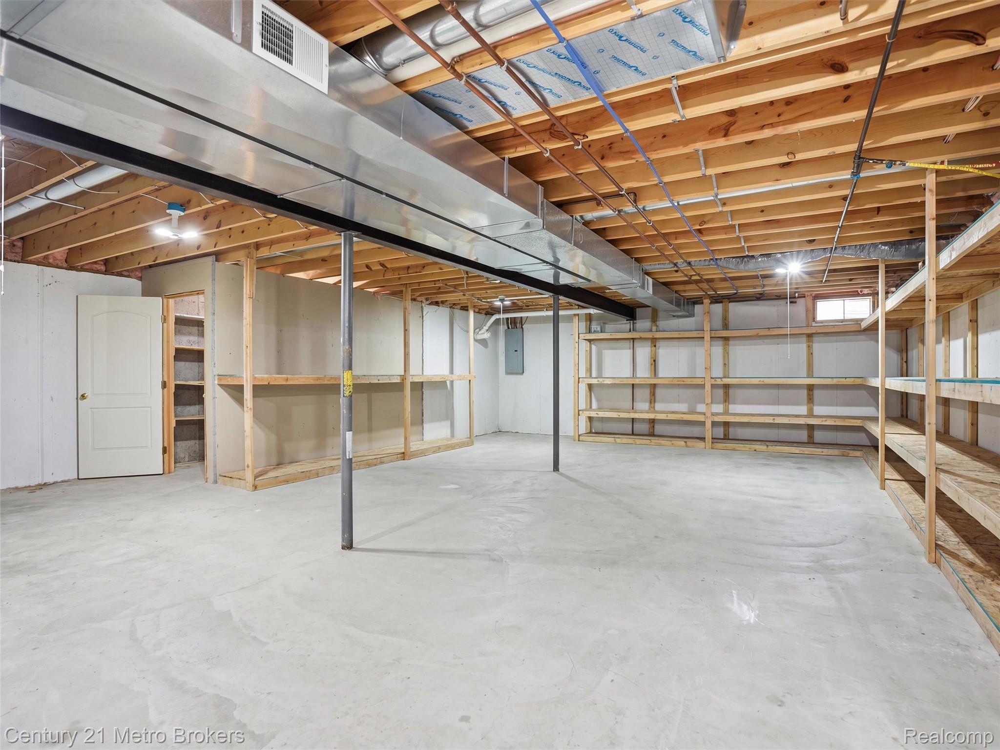11447 North Latson Road Linden, MI 48451 - Photo 30 of 52 Spacious unfinished basement featuring exposed wood joists, concrete flooring, built-in shelving, a full-size door, and exposed ductwork