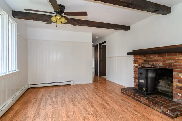 a view of empty room with wooden floor and fireplace