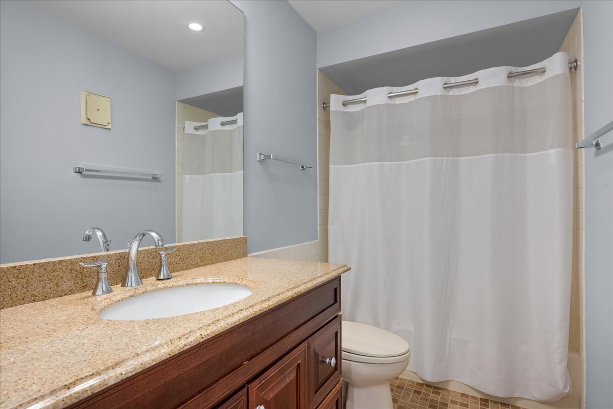1795 Lake Cook Road, Unit 107 Highland Park, IL 60035 - Photo 18 of 26 a bathroom with a granite countertop sink toilet and a mirror