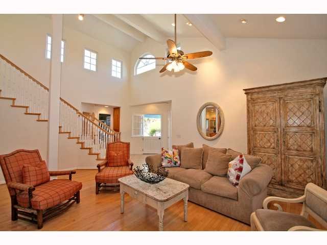 a living room with couches a fireplace and a dining table with wooden floor
