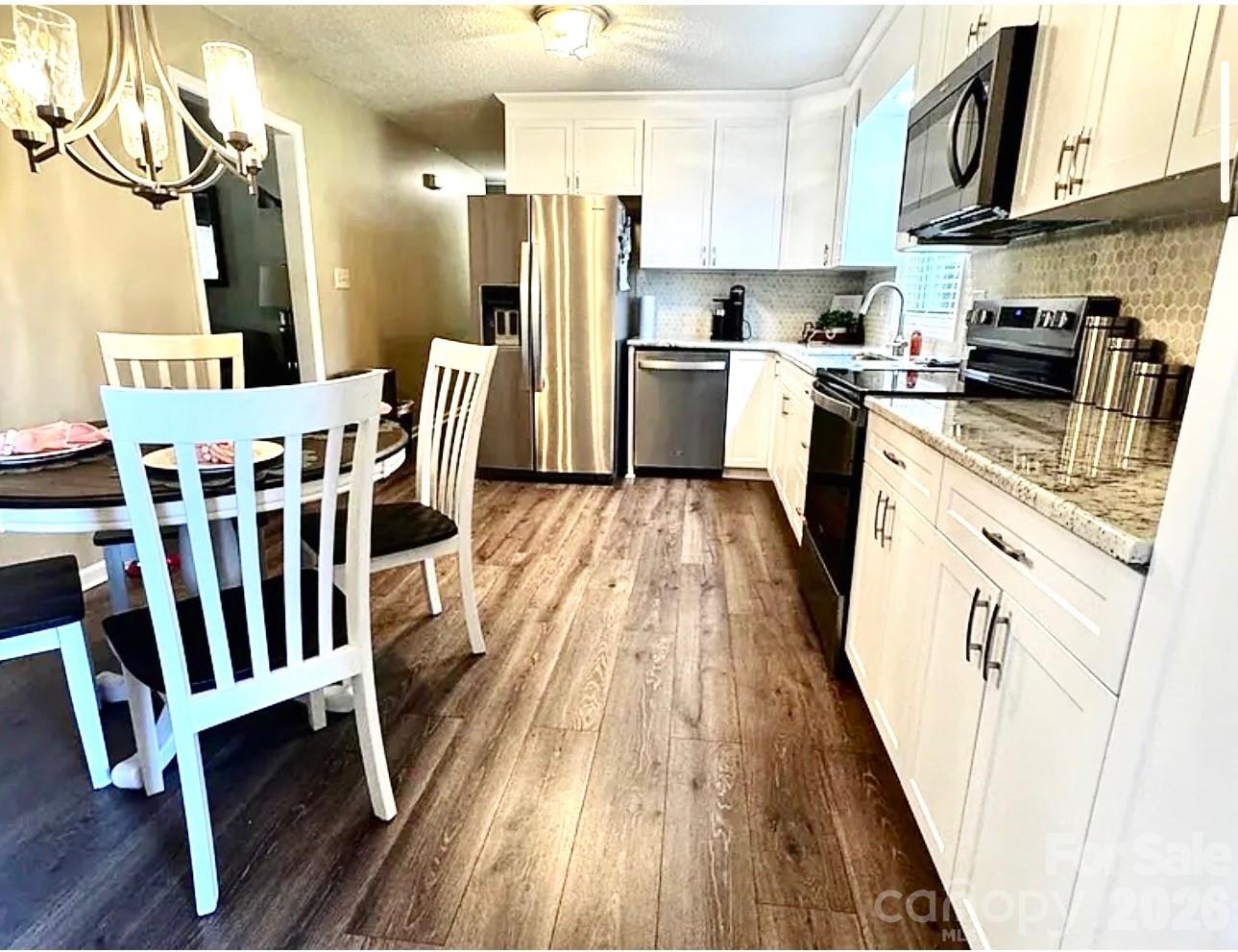 a kitchen with wooden floors stainless steel appliances a stove top oven