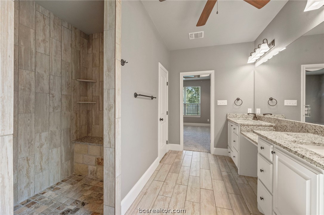 3028 Embers Loop Bryan, TX 77808 - Photo 12 of 26 Full bathroom featuring two vanities, tiled shower, a ceiling fan, and wood tiled floors