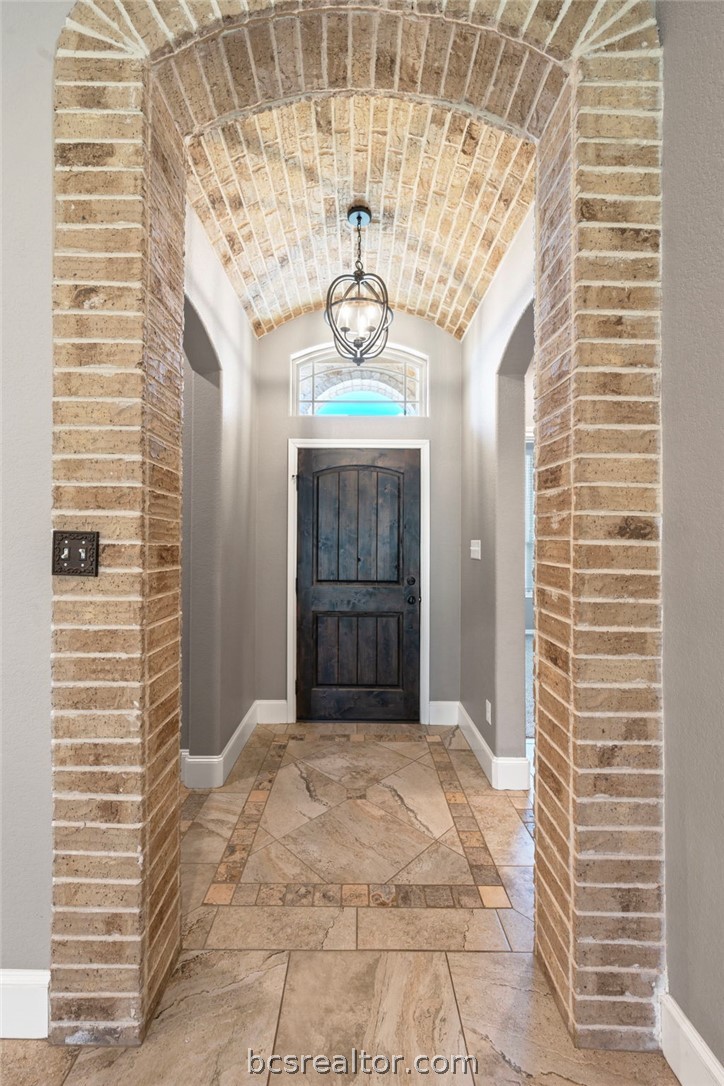 3028 Embers Loop Bryan, TX 77808 - Photo 2 of 26 Entryway featuring inlaid floor details, brick ceiling, and vaulted ceiling