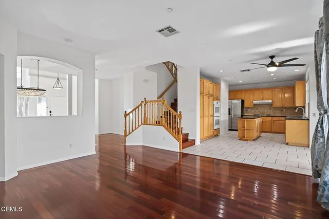 a open kitchen with stainless steel appliances granite countertop a refrigerator a sink a stove a washer and a dining table