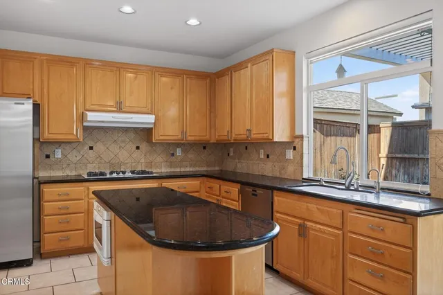 a kitchen with granite countertop a sink and a stove with white countertops