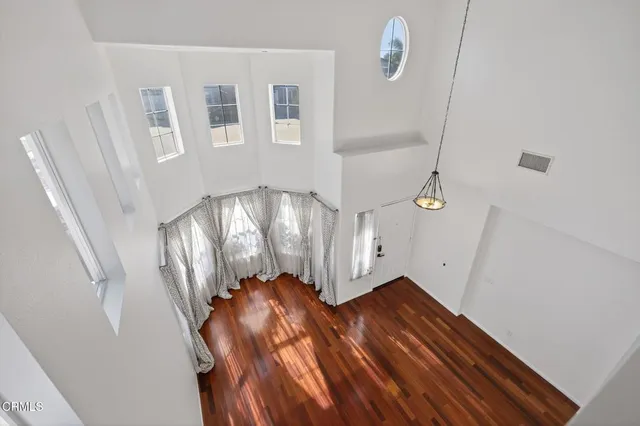 an empty room with wooden floor and a hallway