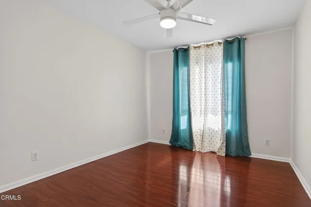 an empty room with wooden floor closet and windows