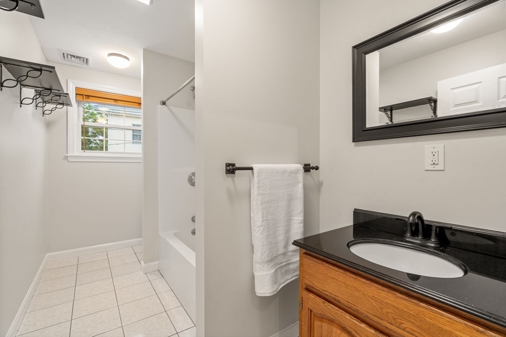 104 Crescent Street, Unit 1 Waltham, MA 02453 - Photo 18 of 30 a bathroom with a granite countertop sink and a mirror