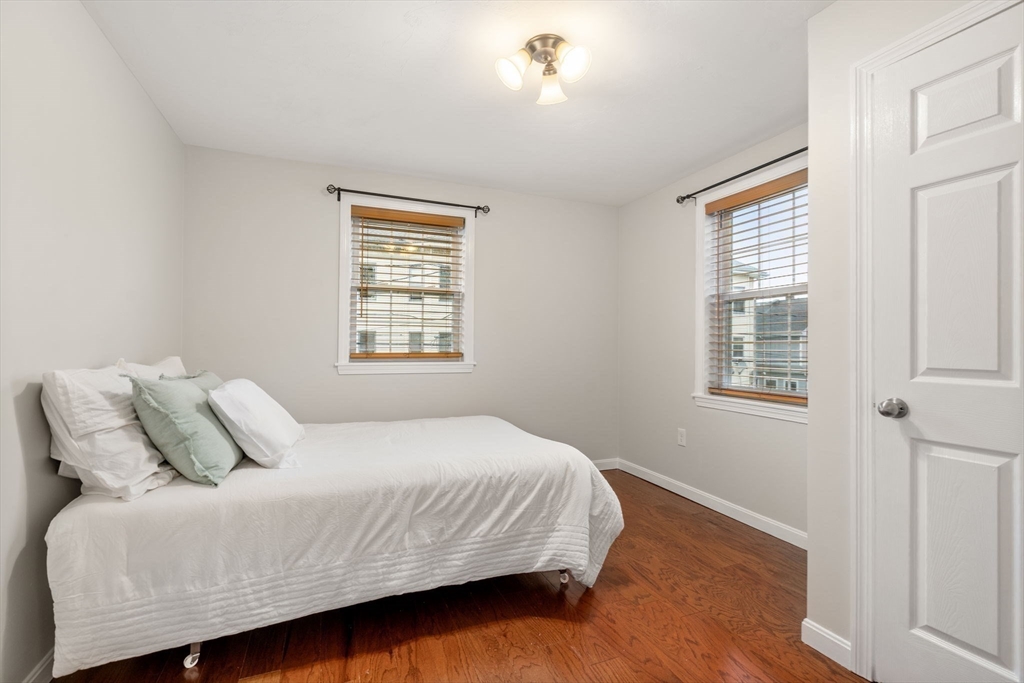 104 Crescent Street, Unit 1 Waltham, MA 02453 - Photo 19 of 30 a bedroom with a bed and wooden floor