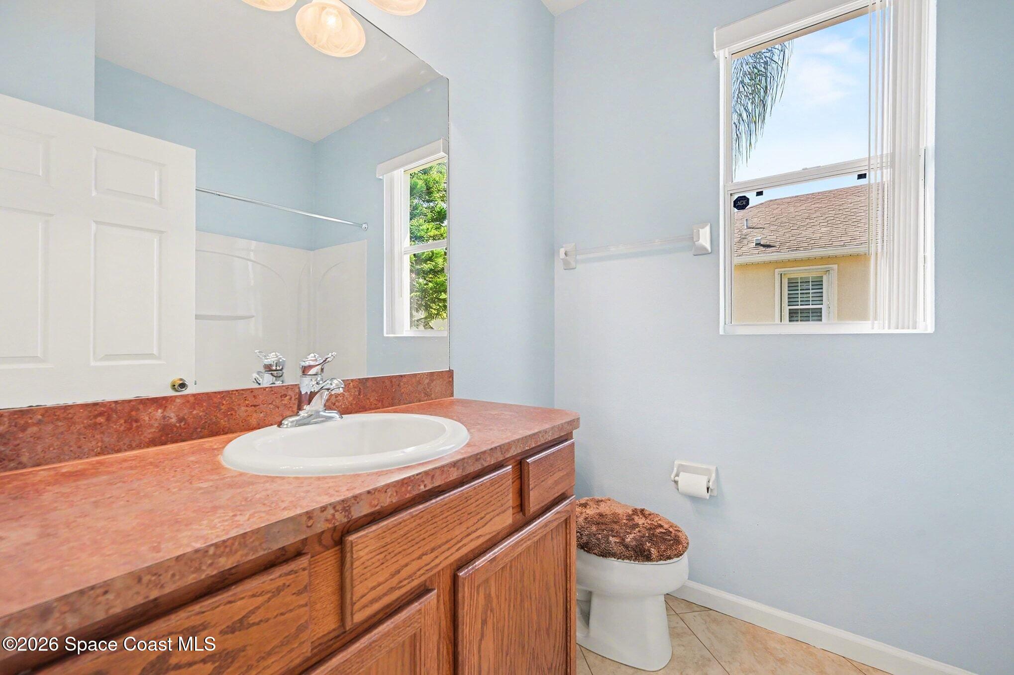 3271 Arden Circle Melbourne, FL 32934 - Photo 25 of 29 a bathroom with a granite countertop sink a toilet and a mirror