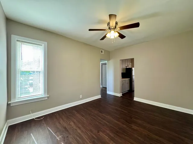 a view of an empty room with wooden floor and a window