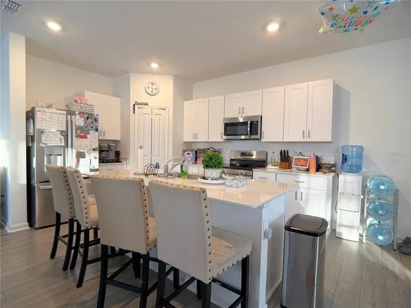 a kitchen with stainless steel appliances a stove a refrigerator a sink dishwasher and a refrigerator with wooden floor