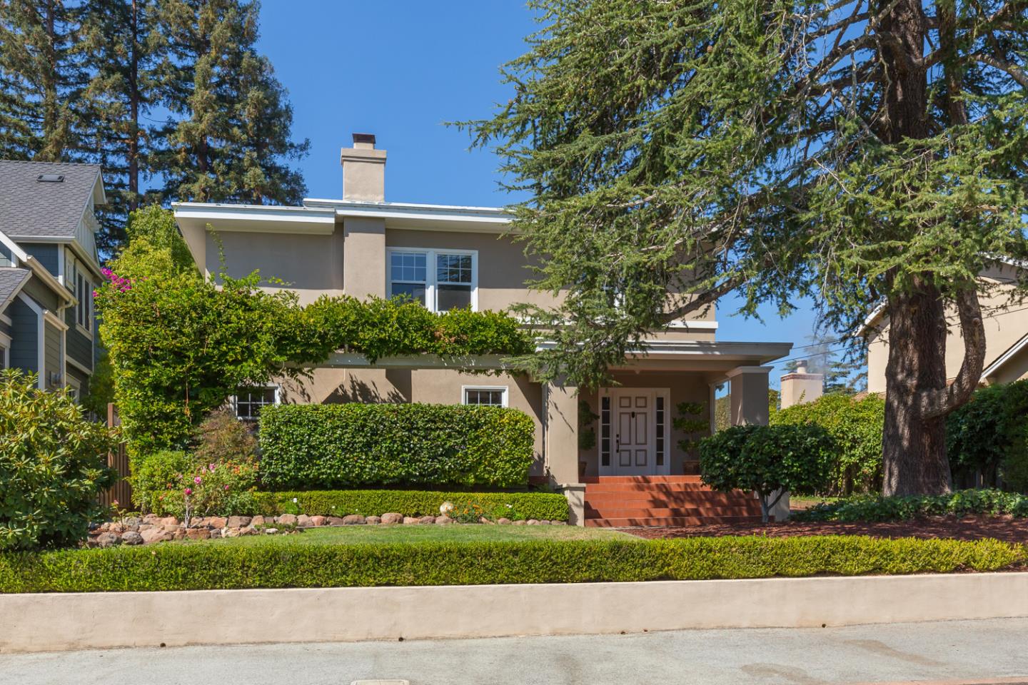 a front view of a house with a yard and potted plants