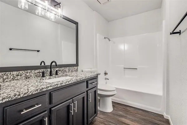 a bathroom with a granite countertop toilet sink and mirror